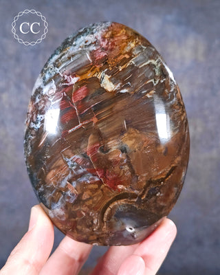 A hand holding a Cosmic Jasper Freeform from Madagascar