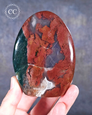 A hand holding a Cosmic Jasper Freeform from Madagascar