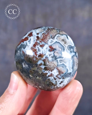 A hand holding an Ocean Jasper Palmstone from Madagascar