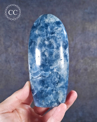 A hand holding a deep Blue Calcite freeform from Madagascar