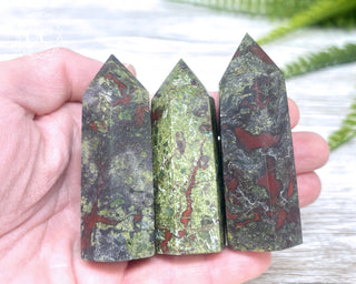 A hand holding three small Dragons Blood Jasper Towers