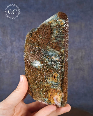 A hand holding a Foitite Tourmaline in Quartz over Feldspar specimen from the Erongo Mountains in Namibia