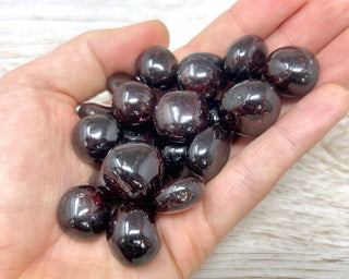 A hand holding a selection of Garnet tumbled crystals 