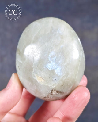 A hand holding a Garnierite Green Moonstone Palmstone from Madagascar