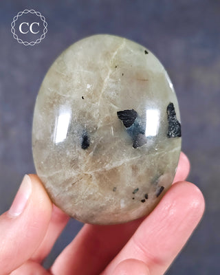 A hand holding a Garnierite Green Moonstone Palmstone from Madagascar