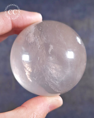 A hand holding a Girasol Quartz Sphere