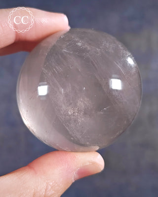 A hand holding a Girasol Quartz Sphere