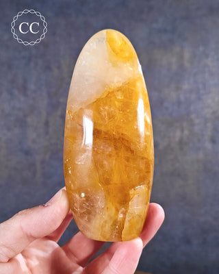 A hand holding a Golden Healer freeform from Madagascar