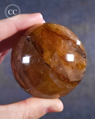 A hand holding a Golden Healer Sphere from Madagascar
