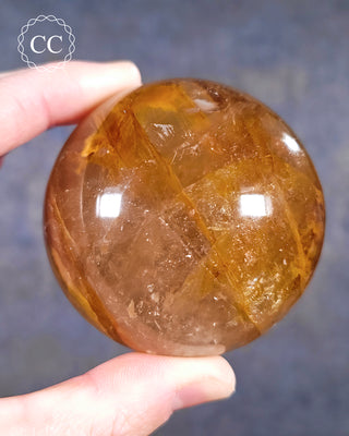A hand holding a Golden Healer Sphere from Madagascar 