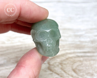 Fingers holding a mini Green Aventurine Crystal Skull Carving