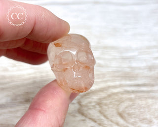 Fingers holding a Hematoid Quartz crystal skull 