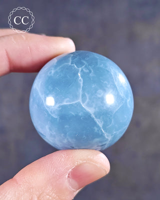 A hand holding a Blue Opal Sphere from Rajasthan, India