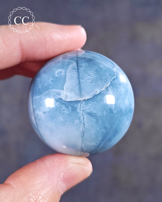A hand holding a Blue Opal Sphere from Rajasthan, India