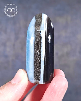 A hand holding a banded Blue Opal Freeform from Rajasthan, India