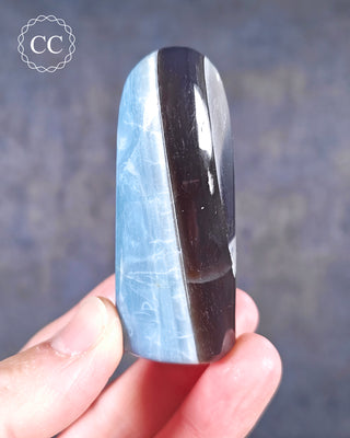 A hand holding a banded Blue Opal Freeform from Rajasthan, India