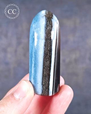 A hand holding a banded Blue Opal Freeform from Rajasthan, India