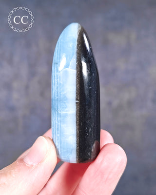 A hand holding a banded Blue Opal Freeform from Rajasthan, India