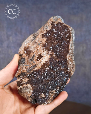 A hand holding an iridescent Calcite specimen from Oskaloosa, Iowa, USA