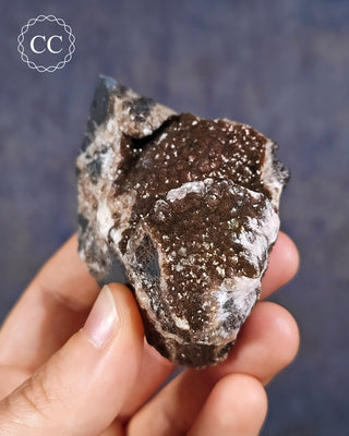 A hand holding an iridescent Calcite specimen from Oskaloosa, Iowa, USA
