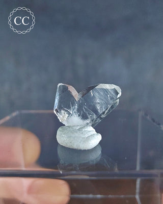 A Japan Law Twin Quartz from Namibia displayed on a clear box 