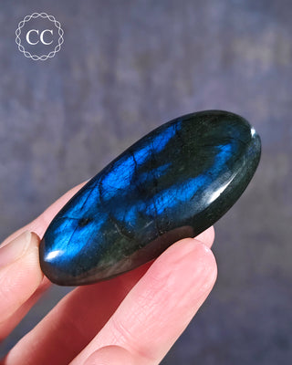 A hand holding a Labradorite Palmstone from Madagascar