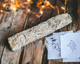 Large white sage stick on a wooden table with fairy lights