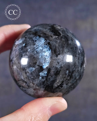 A hand holding a Larvikite Sphere from India