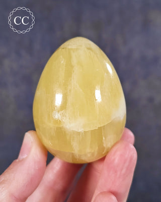 A hand holding a Lemon Calcite Egg from Pakistan
