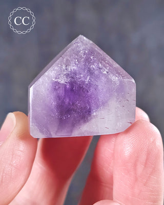 A hand holding a Madagascan Amethyst Tower