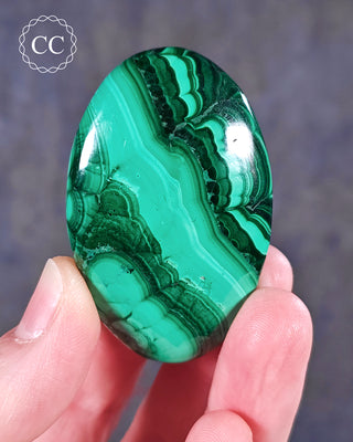 A hand holding a Malachite palmstone