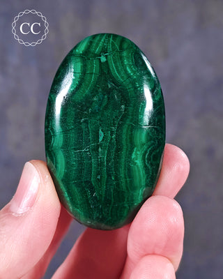 A hand holding a Malachite palmstone