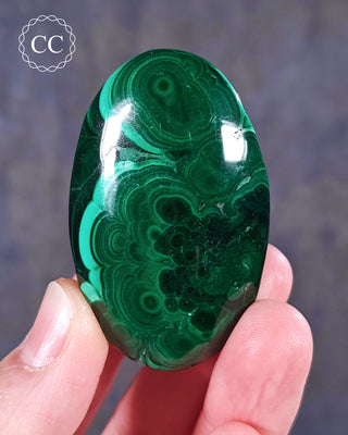 A hand holding a Malachite palmstone