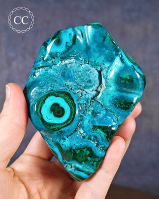 A hand holding a Malachite & Chrysocolla Polished Freeform