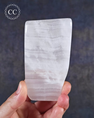 A hand holding a Mangano Calcite freeform 
