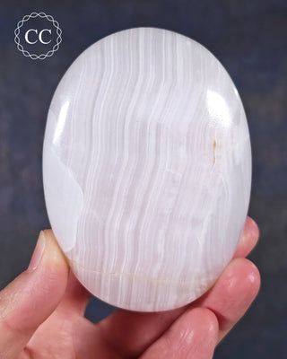 A hand holding a Mangano Calcite Chunky Palmstone from Pakistan