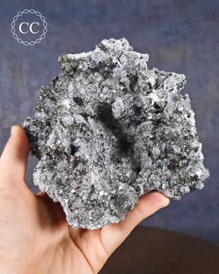 A hand holding a large Calcite with Marcasite inclusions is from the Linwood Mine, Buffalo, Iowa