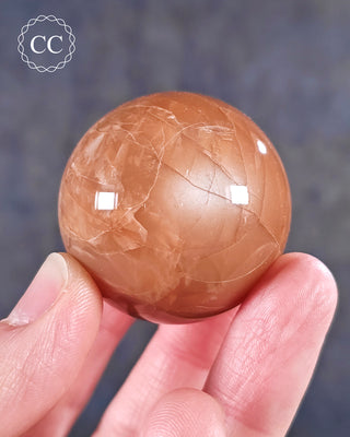 A hand holding a Moonstone Sphere