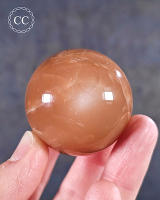 A hand holding a Moonstone Sphere