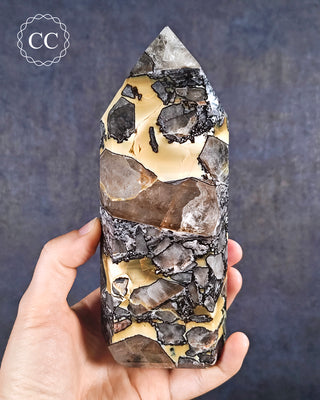 A hand holding a Mosaic Quartz tower from Brazil