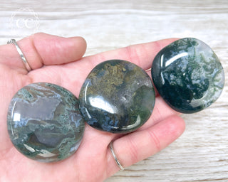 A hand holding three Moss Agate Palmstones