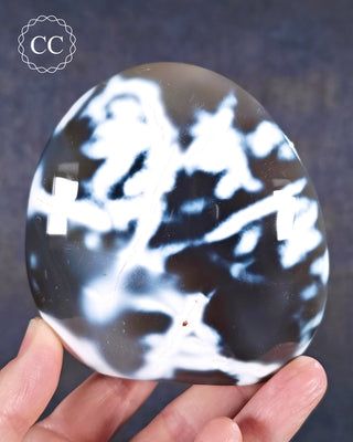 A hand holding an Orca Agate freeform from Madagascar