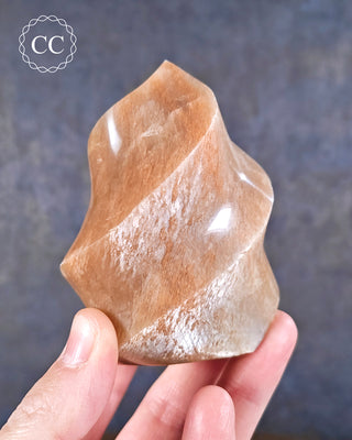 A hand holding a Peach Moonstone Flame from Madagascar