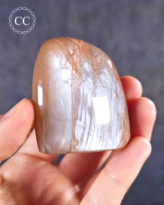 A hand holding a Peach Moonstone Freeform from Madagascar