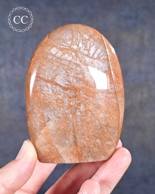A hand holding a Peach Moonstone Freeform from Madagascar