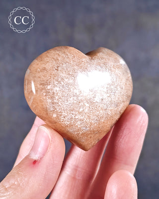 A hand holding a Peach Moonstone Heart from Madagascar