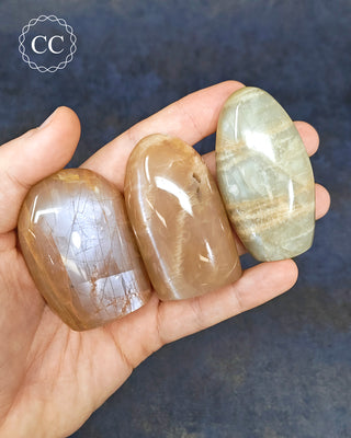 Peach Moonstone Small Freeforms in hand on blue background
