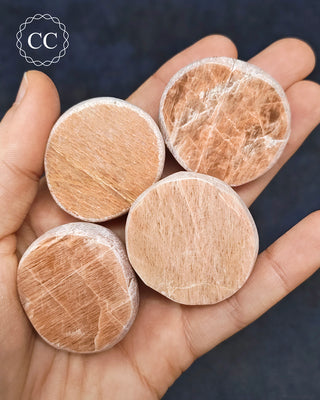 A hand holding 4 Peach Moonstone Dragon Eggs from Madagascar