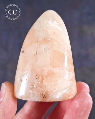 A hand holding a Peach Stilbite Freeform from India 