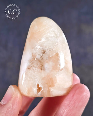 A hand holding a Peach Stilbite Freeform from India 